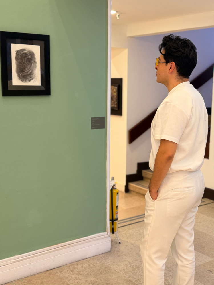 El artista Alejandro Londoño, frente a su obra "Voilà" en la exposición del gran salón BAT, en la cámara de comercio de Medellín.